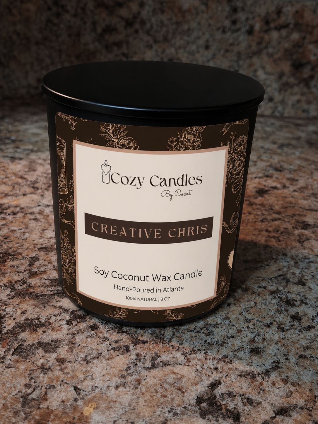 A jar candle labeled , Creative Chris, Soy Coconut Wax Candle, sitting on a speckled granite countertop.