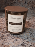 A Cozy Candles soy coconut wax candle in a brown glass jar with a matching brown lid and a cream label reading 'Daring Dame', placed on a speckled granite countertop.